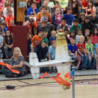 model plane in flight in front of a crowd