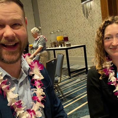 Two people with flower necklaces smiling.