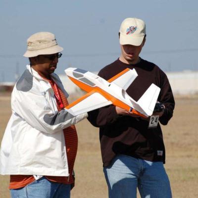 Two people holding and checking a model plane.