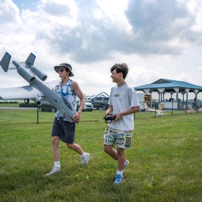 Two people walking with a model plane.