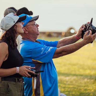 A young woman learns how to fly a model airplane from a mentor.