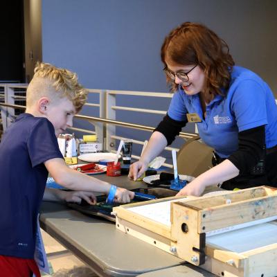Child painting a printing press at Tinkerfest