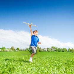 A young child runs with a model plane.