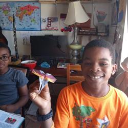 A young student shows off his paper airplane.