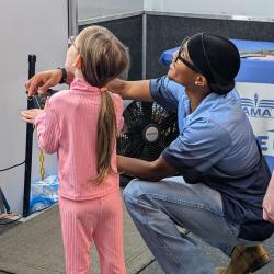 Ashton teaching young visitor how to fly simulator. 
