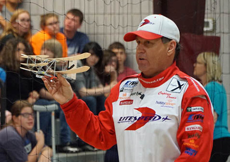 a man holding a wright flyer model in front of a crowd