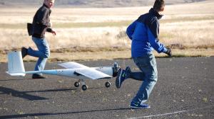 Two young pilots run alongside a model plane.