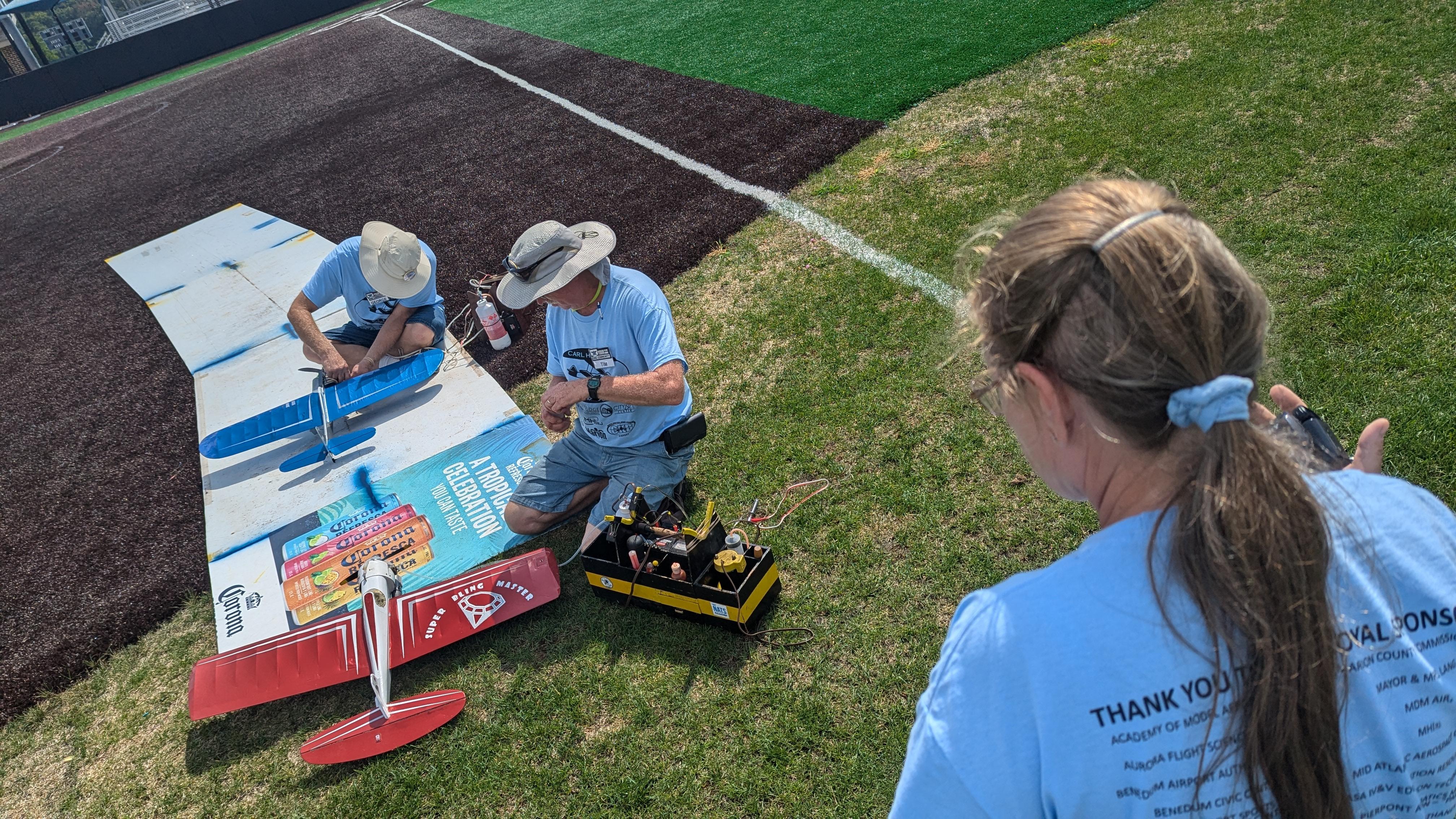 Three pilots prepare their control line planes for a flight