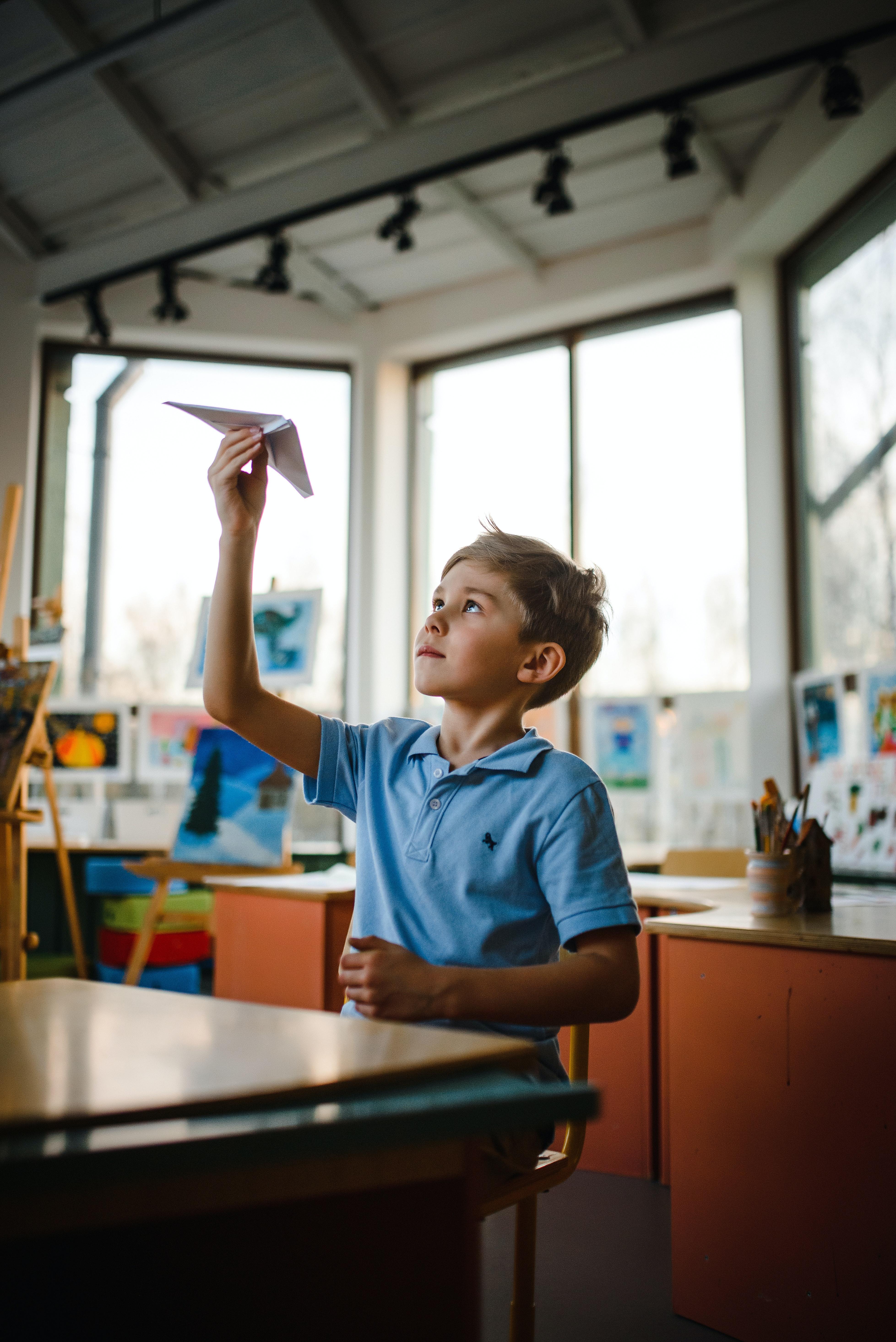 A student looks at his paper airplane.