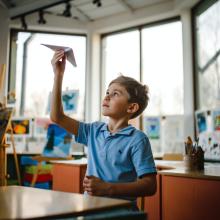 A student looks at his paper airplane.